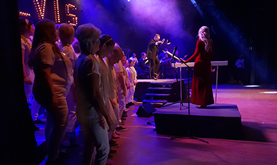 Daniel steppar under Blue Suede Shoes, producent och dirigent Johanna Grüssner tittar på. Dans och koreografi: Sofia Enros och Daniel Johansson, Mildreds kompani, Åland ELVIS Ålands projektkör 2019 swingdans Boogie Woogie Lindy Hop St Louis Shag Autentisk Jazz Stepp Tap