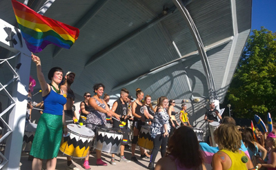 Sofia Enros verksamhetsledare för åländska hbt-föreningen Regnbågsfyren och projektledare för Åland Pride på scen tillsammans med slagverksorkestern Kiriaka Foto: Daniel Johansson Mariehamn 22 augusti 2015